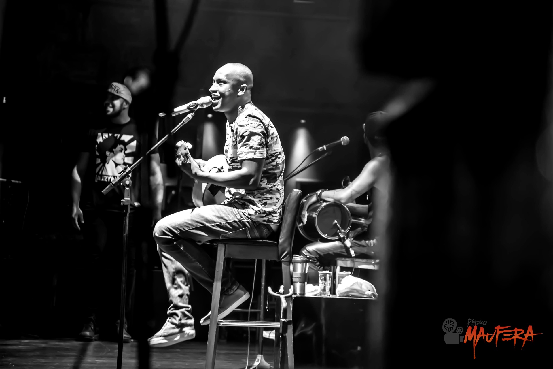 Thiaguinho sentado tocando cavaco sorrindo P&B