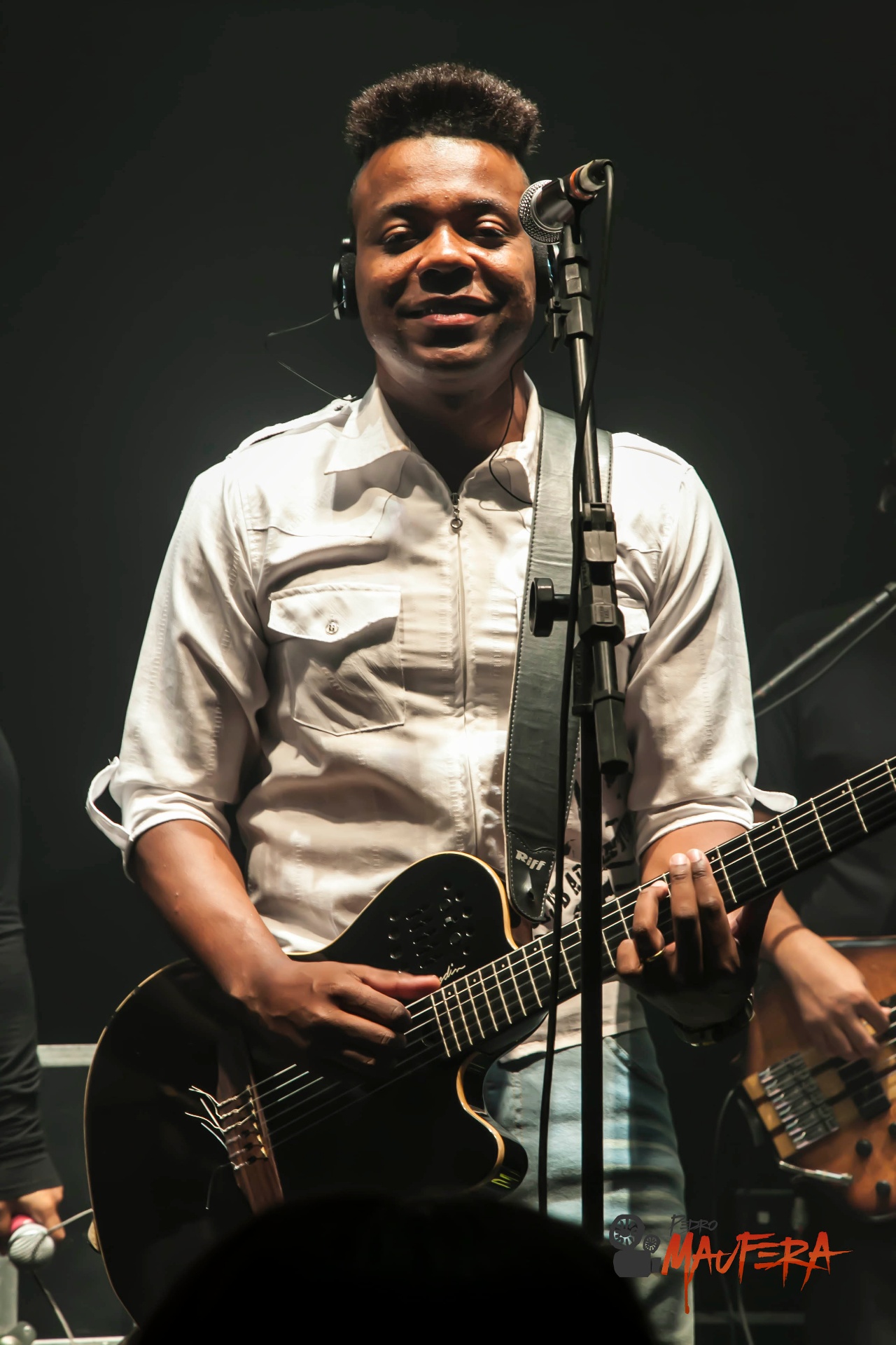 Guitarrista sorrindo com camisa branca